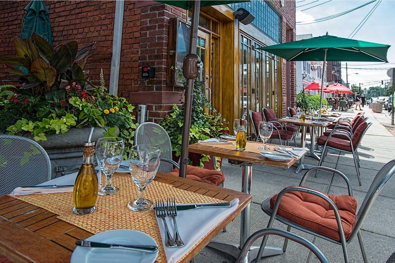 Outdoor dining in front of the restaurant with set tables and umbrellas