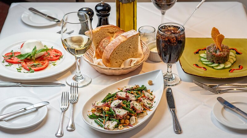 Multiple appetizers with a basket of bread and drinks